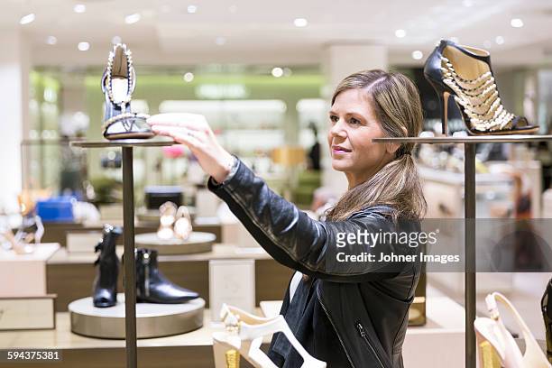 woman in shoe shop - schoenenwinkel stockfoto's en -beelden