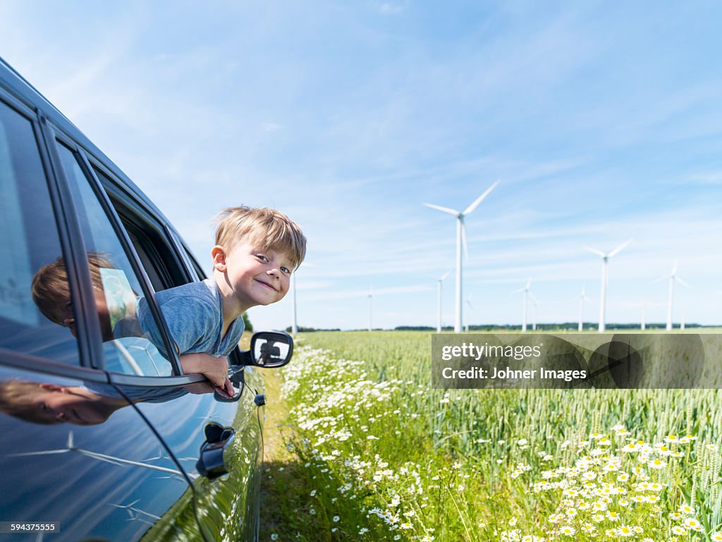 Smiling boy in car near wind turbines