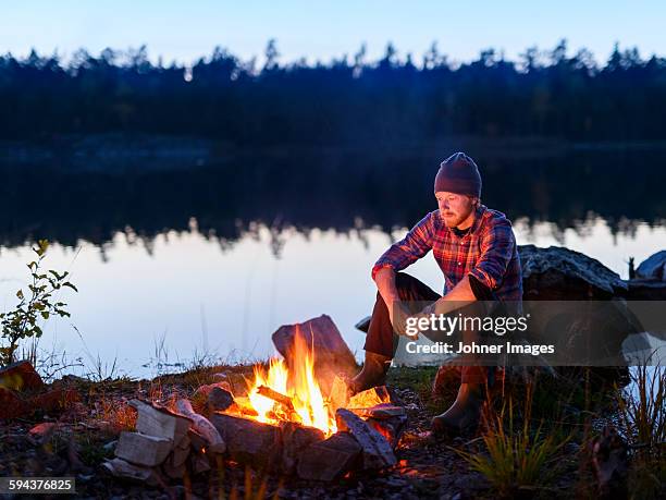 man having campfire - log fire stock pictures, royalty-free photos & images
