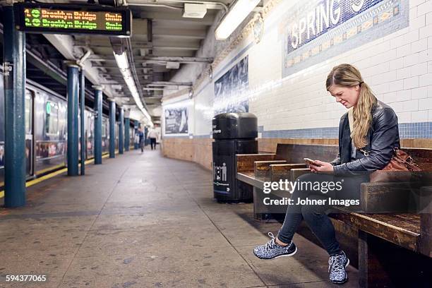 woman using cell phone on train station. new york city, usa - plataforma de estação de metro imagens e fotografias de stock