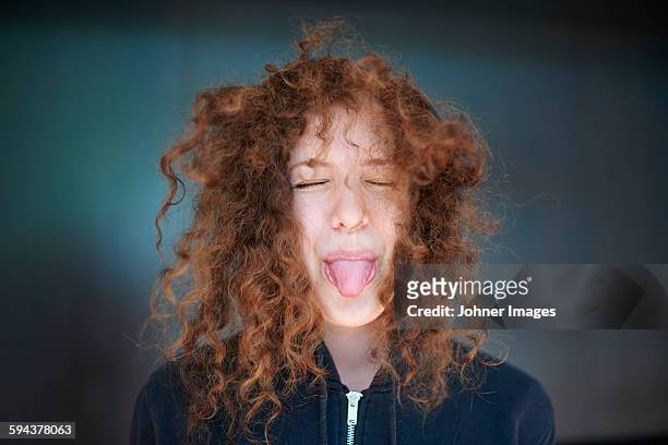 young woman sticking out tongue - messy hair stock-fotos und bilder