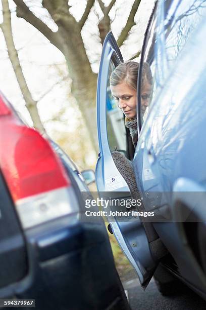 woman trying to leave car in tiny parking space - narrow stockfoto's en -beelden