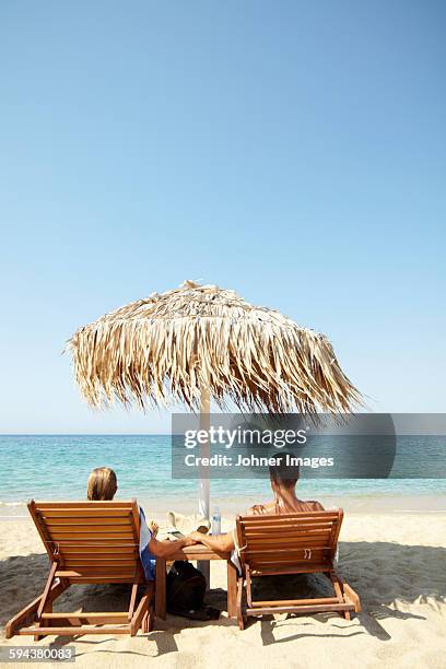 couple relaxing on beach - sombrilla playa fotografías e imágenes de stock