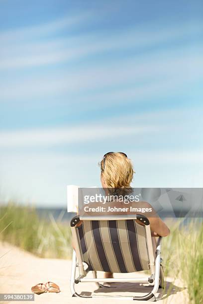 woman reading book on beach - beach book reading stock-fotos und bilder