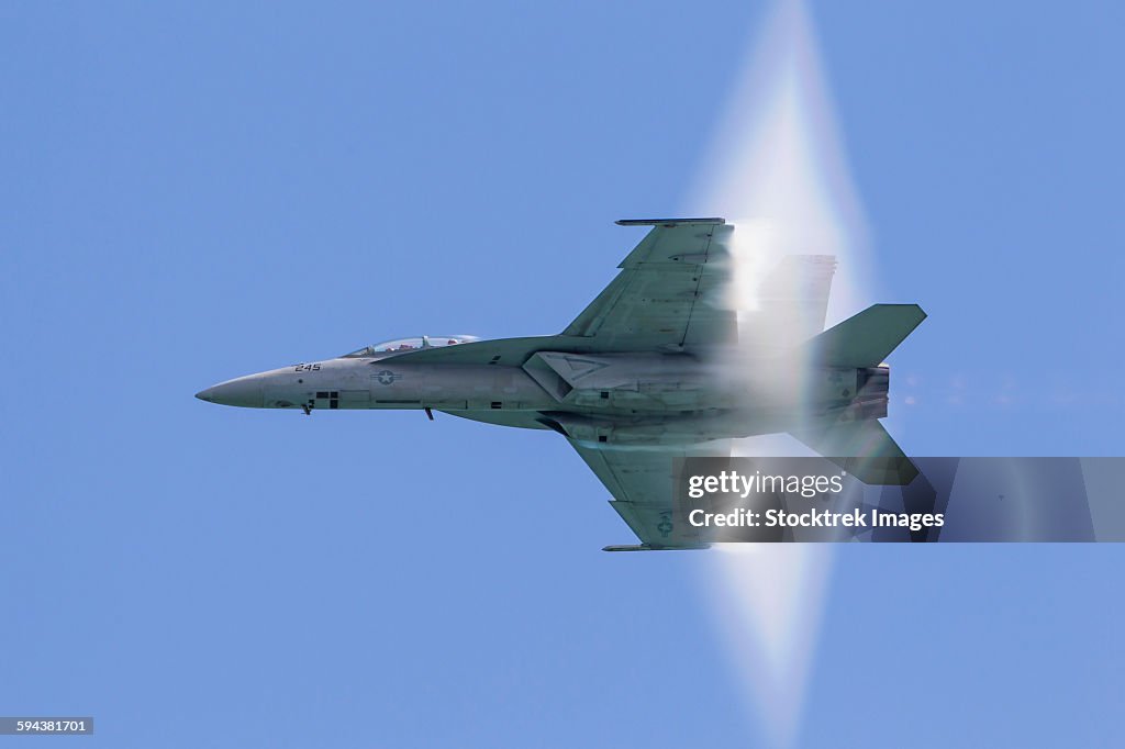 A U.S. Navy F/A-18F Super Hornet flies by at high transonic speed.