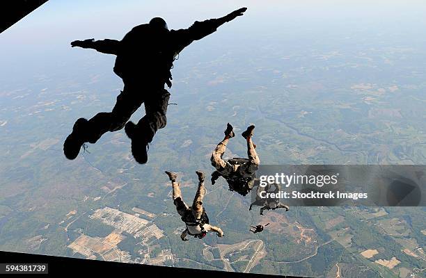 navy seals jump from the ramp of a c-17 globemaster iii over virginia. - paratrooper stockfoto's en -beelden