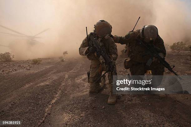 soldiers brace for the impact of a cloud of sand and rocks from a landing ch-53 super stallion. - campamento de instrucción militar fotografías e imágenes de stock