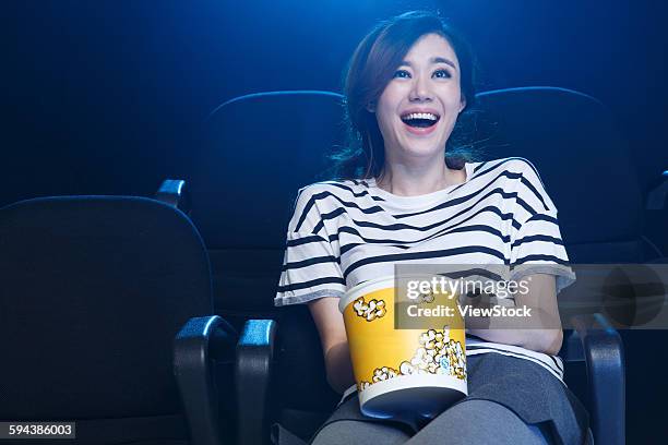 a young woman is watching a movie in the cinema. - asian cinema stock pictures, royalty-free photos & images