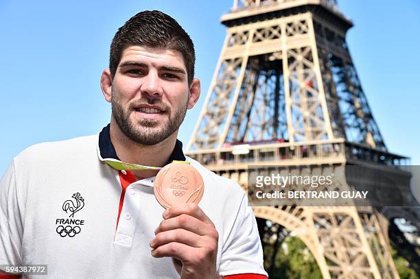 French judoka Cyrille Maret poses with his bronze medal on August 23 in front of the Eiffel tower in Paris. France's Olympic team landed in Paris on...