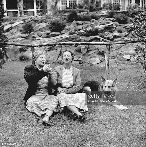 Teacher and author Helen Keller rests on a garden lawn with a friend and her guide dog. Keller achieved wide recognition by overcoming blindness and...