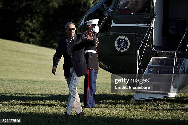 President Barack Obama, left, waves after exiting Marine One on the South Lawn as he returns to the White House in Washington, D.C. On Tuesday, Aug....