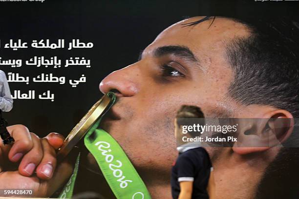 Child passes by a picture during a ceremony to welcome home Jordanian Olympic gold medallist Ahmad Abu Goush and other olympic mission members upon...