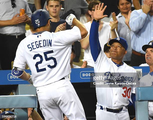 Rob Segedin of the Los Angeles Dodgers is greeted by manager Dave Roberts after a solo home run in the second inning of the game against the San...