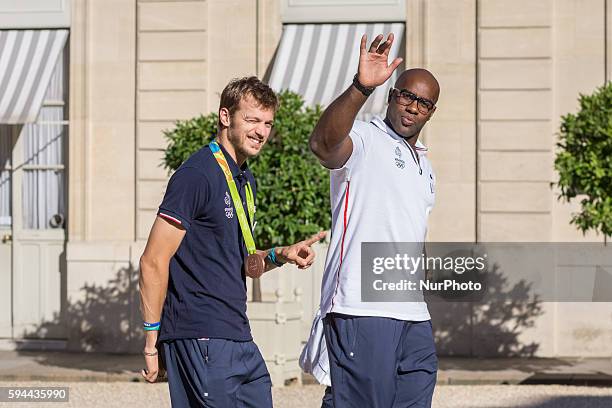 French gold medal winner and judoka Teddy Riner flanked by French 200m bronze medallist Christophe Lemaitre gestures as they arrive at the Elysee...