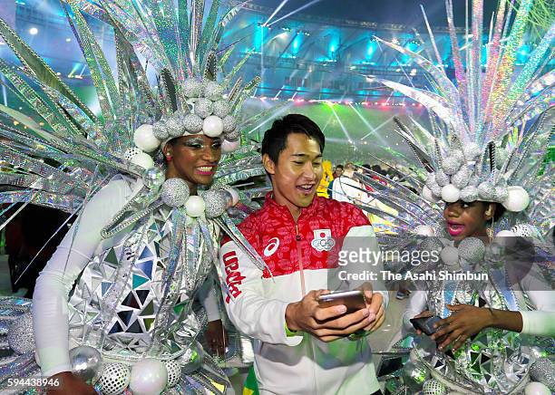 Shota Iizuka of Japan poses for selfie photographs with samba dancers during the Closing Ceremony on Day 16 of the Rio 2016 Olympic Games at Maracana...