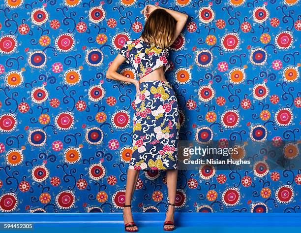 woman wearing print dress against print background - mode stock-fotos und bilder