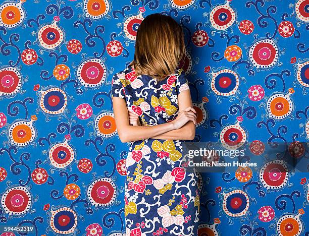 woman wearing print dress against print background - print dress stock pictures, royalty-free photos & images