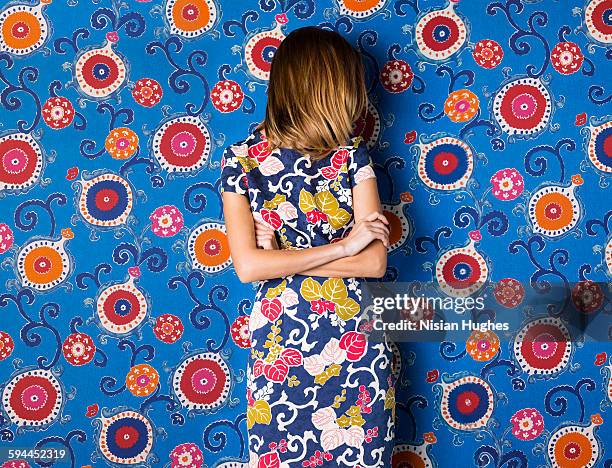 woman wearing print dress against print background - floral pattern dress stock pictures, royalty-free photos & images