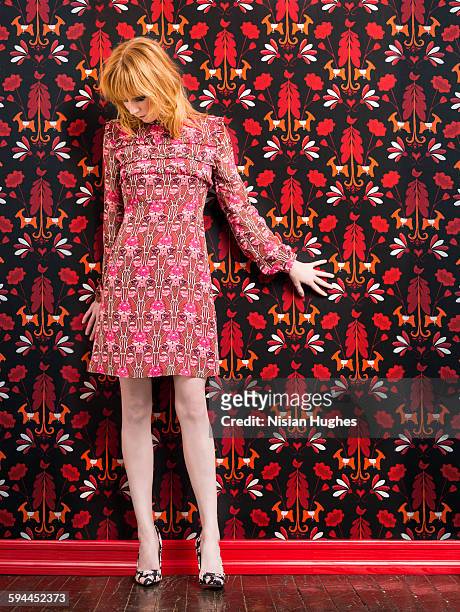 woman wearing print dress against print background - vrouw behangen stockfoto's en -beelden