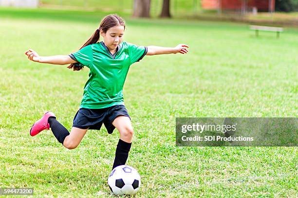intensa ragazza preteen ispanica calcia pallone da calcio - calciare foto e immagini stock