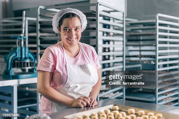 bénévole avec un handicap intellectuel travaillant à l’atelier de boulangerie - boulangerie industrielle photos et images de collection
