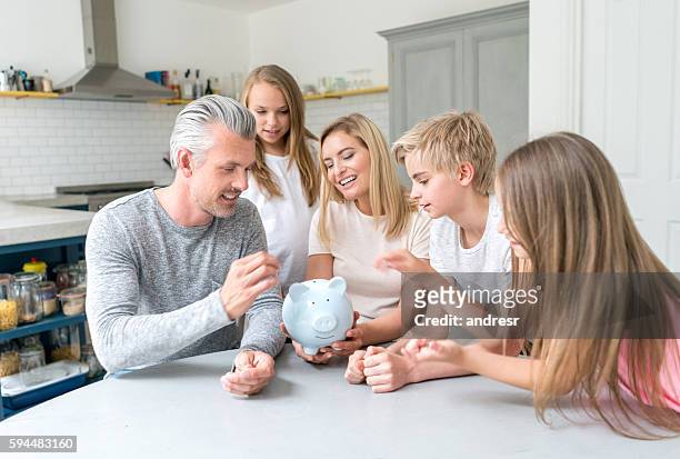 family saving money in a piggybank - family savings stock pictures, royalty-free photos & images