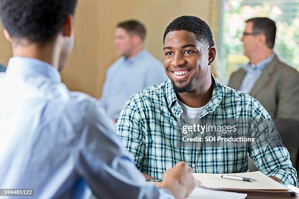 lächelnde afroamerikanische junge erwachsene bei einem vorstellungsgespräch - african american interview stock-fotos und bilder