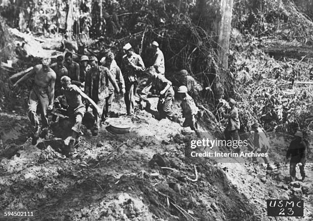 American Marines carry a wounded buddy over a rough trail to be evacuated to a rear base for medical attention in Bougainville, Papua New Guinea,...