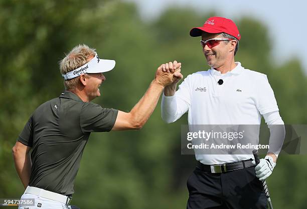 Crown Prince Frederik of Denmark is congratulated by his playing patrtner Soren Kjeldesn after his tee-shot on the first hole during the Pro Am prior...