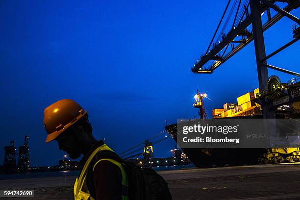 Worker stands near the Hapag-Lloyd Holding AG Prague Express cargo ship at the Cia Siderurgica Nacional SA Sepetiba Tecon terminal inside the Port of...