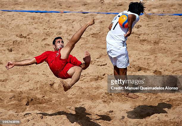 Mohammadali Mokhtari of Iran attempts a scissor kick shot on goal in front Teruki Tabata of Japan during the Continental Beach Soccer Tournament...