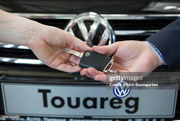 Key handover after a car purchase in a Volkswagen car dealer in Bonn. The photo shows the hands of the seller and of a customer female during the key...