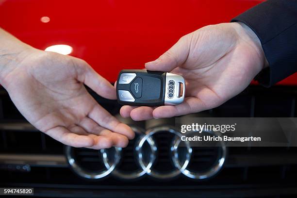 Key handover after a car purchase in a AUDI car dealer in Bonn. The photo shows the hands of the seller and of a customer female during the key...