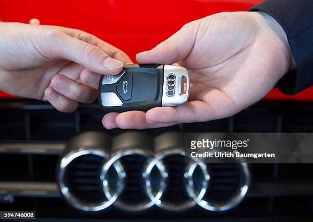 Key handover after a car purchase in a AUDI car dealer in Bonn. The photo shows the hands of the seller and of a customer female during the key...