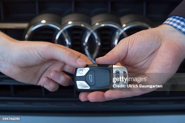 Key handover after a car purchase in a AUDI car dealer in Bonn. The photo shows the hands of the seller and of a customer female during the key...