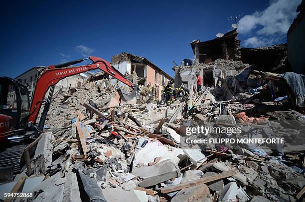 Rescuers and firemen inspect the rubble of buildings in Amatrice on August 24, 2016 after a powerful earthquake rocked central Italy. The earthquake...