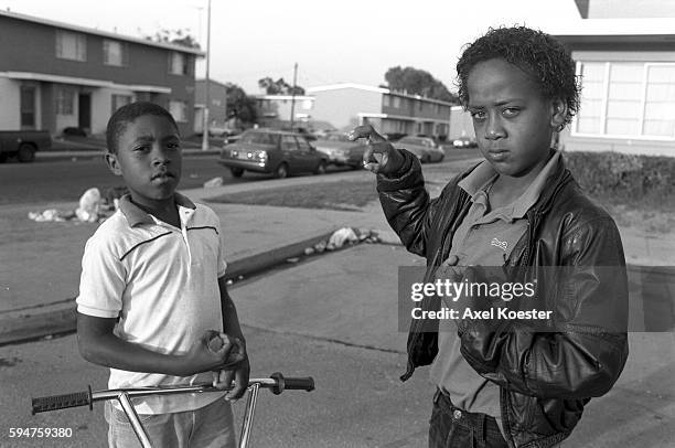 Two young members of Grape Street pose with their trademark 'g' hand sign. The Grape Street Watts Crips are a mostly African American street gang...