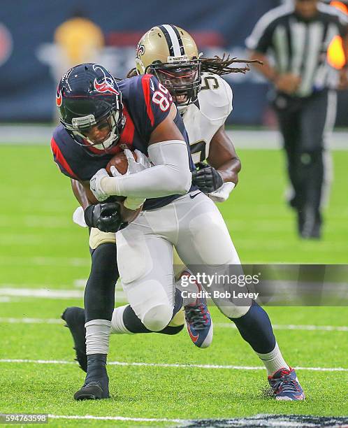 Stephen Anderson of the Houston Texans is tackled by Dannell Ellerbe of the New Orleans Saints after a reception during a preseason NFL game at NRG...