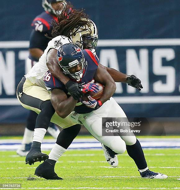 Lamar Miller of the Houston Texans is tackled by Dannell Ellerbe of the New Orleans Saints during a preseason NFL game at NRG Stadium on August 20,...