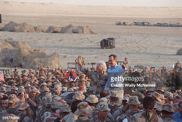 President George H.W. Bush waves with wife, Barbara, as they are surrounded by U.S. Troops at a U.S. Base in Saudi Arabia, Thanksgiving Day 1990.