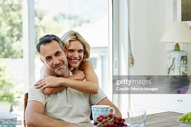 smiling woman embracing man at home - 40 44 años fotografías e imágenes de stock