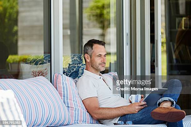 man sitting on sofa at patio - coffee on patio stock pictures, royalty-free photos & images