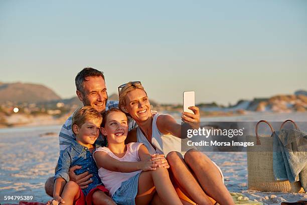 family posing for selfie on beach - smartphone strand stock-fotos und bilder