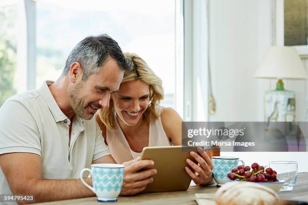 happy couple using digital tablet - couple tablet house stock-fotos und bilder
