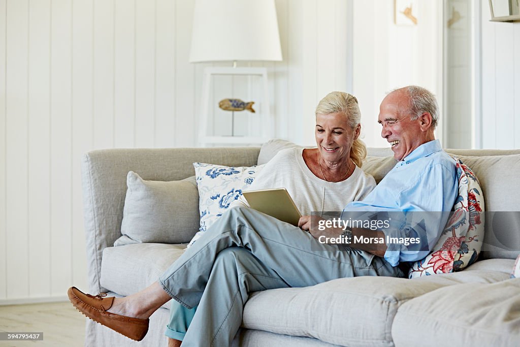 Smiling senior couple using digital tablet at home