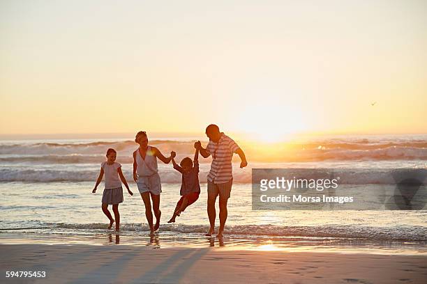 parents with children enjoying vacation on beach - four people stock pictures, royalty-free photos & images