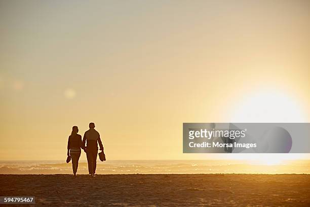 senior couple walking on beach - old man silhouette stock-fotos und bilder
