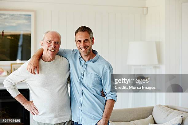portrait of smiling father and son at home - erwachsene person stock-fotos und bilder
