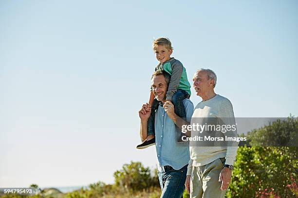 happy three generation males walking on field - dad son stock pictures, royalty-free photos & images
