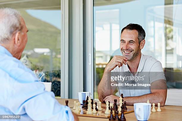 man playing chess with father at patio - playing chess stock-fotos und bilder